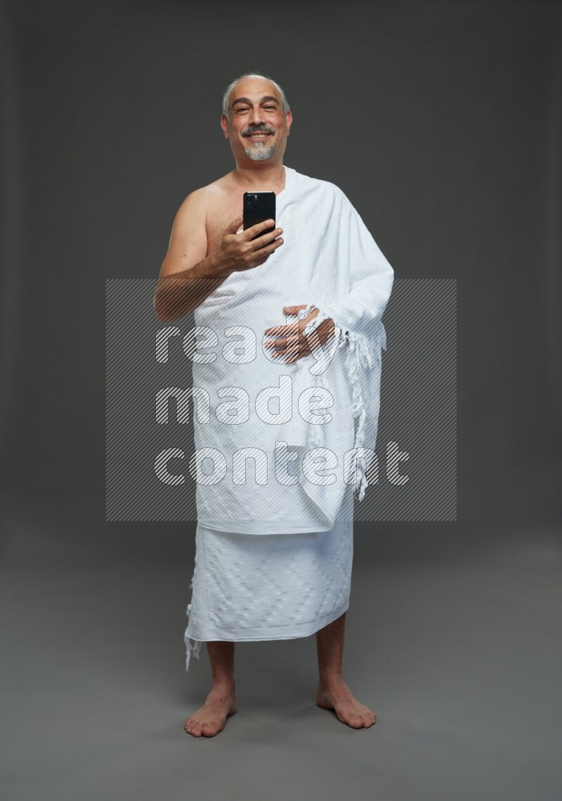 A man wearing Ehram Standing taking selfie on gray background
