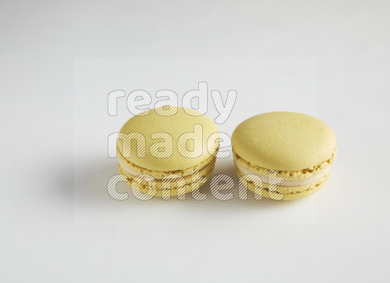 45º Shot of two Yellow Lime macarons on white background