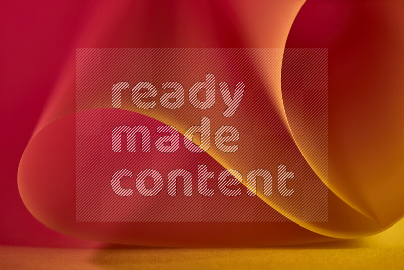 An abstract art piece displaying smooth curves in gold and red gradients created by colored light