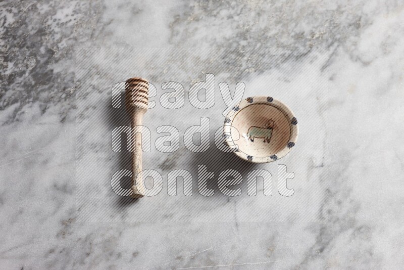 Decorative pottery bowl with wooden honey dipper on the side on grey marble background