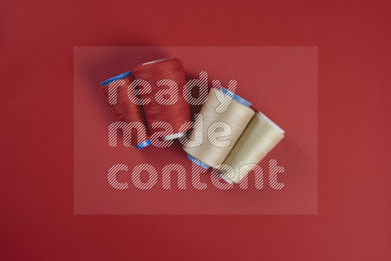 A brown and red collection of sewing and tailoring tools arranged on a red background