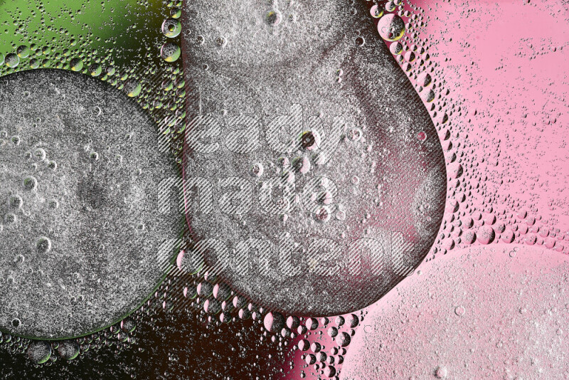 لقطات مقربة لفقاعات من الزيت على سطح الماء باللون الأخضر والوردي