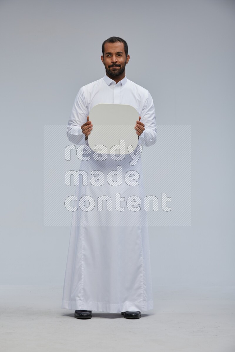 Saudi man wearing Thob standing holding social media sign on Gray background
