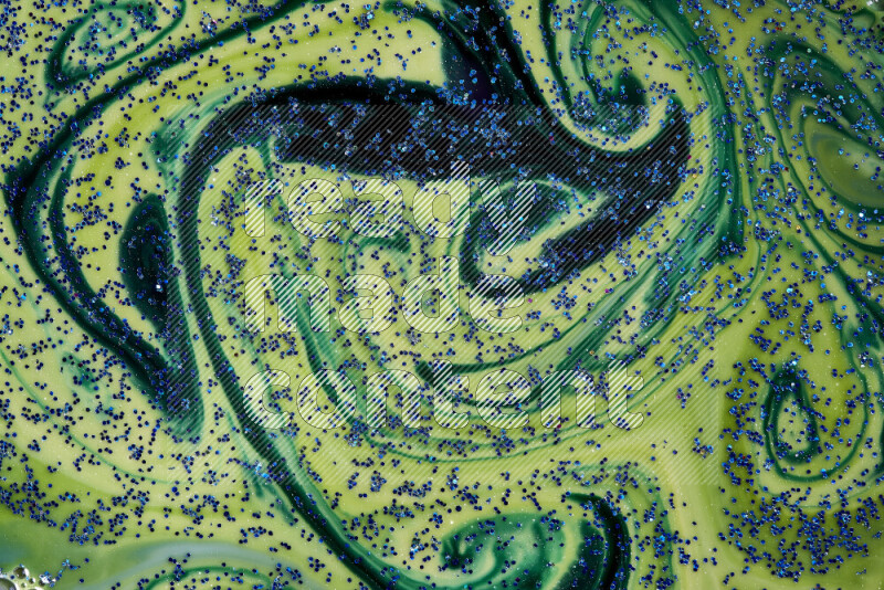 A close-up of sparkling blue glitter scattered on swirling blue and green background