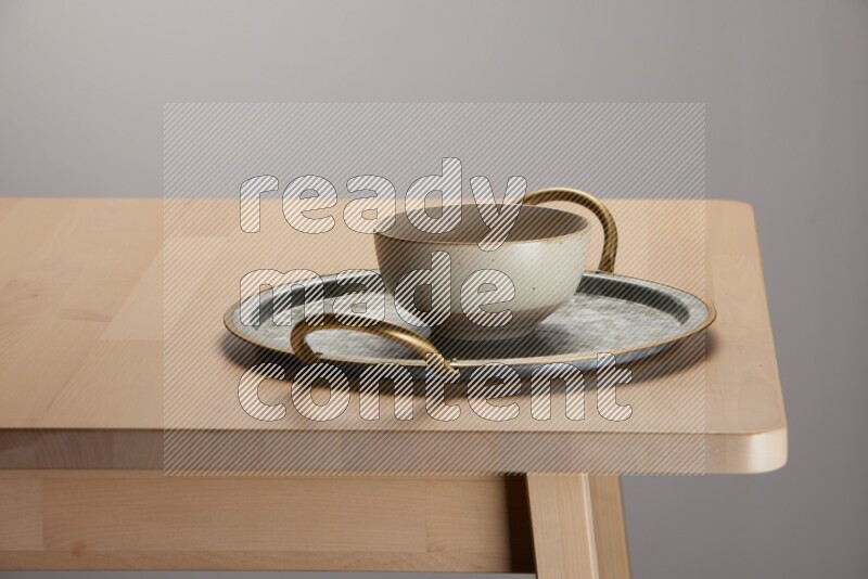 multicolored bowl placed on a rounded stainless steel tray with golden handels on the edge of wooden table