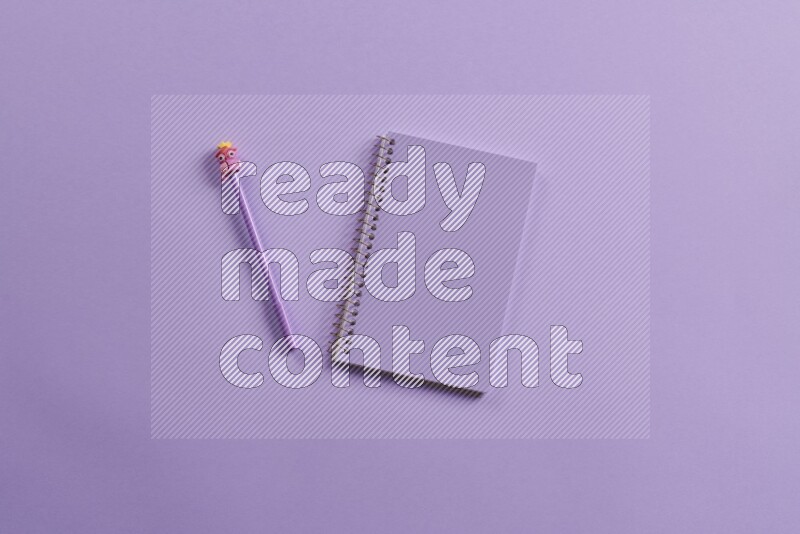 A purple notebook with different school supplies on purple background