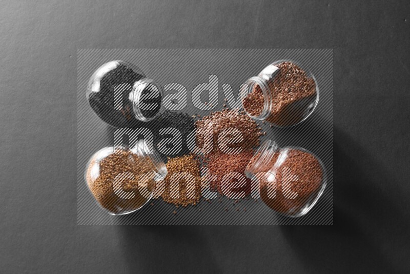 حبة البركة و حبوب الخردل وحبوب الكتان وحب الرشاد في أوعية زجاجية علي خلفية سوداء