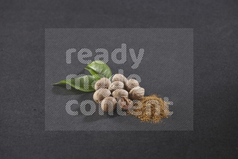 Nutmeg seeds with nutmeg powder beside it on a black flooring in different angles