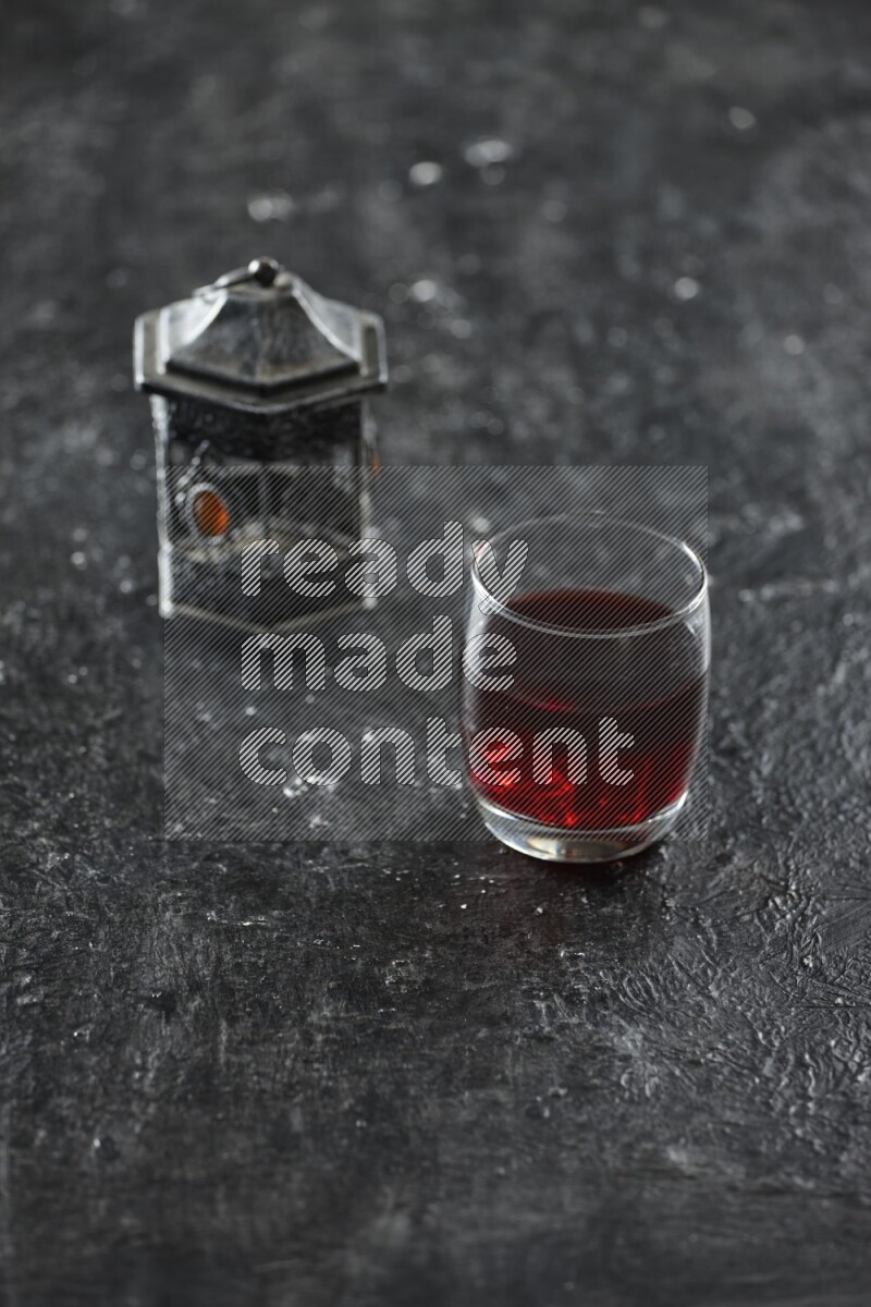 فانوس فضي مع مشروبات مختلفة وتمر ومكسرات وسبحة صلاة وقرآن على خلفية سوداء