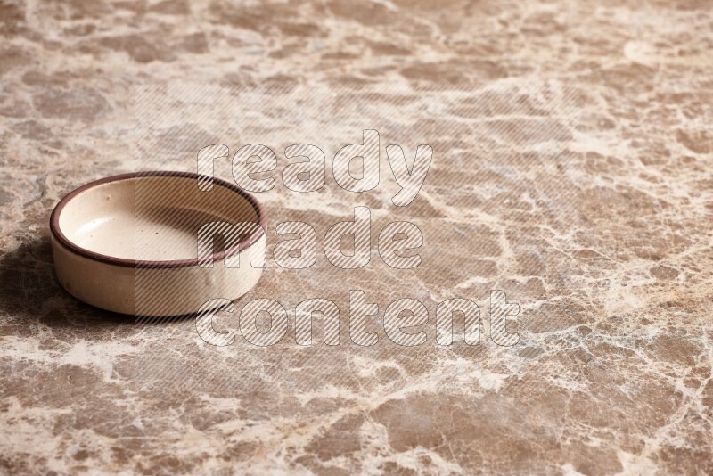 A beige pottery oven plate on beige marble background