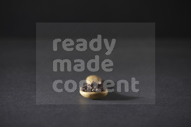 حبوب القرنفل في ملعقة خشبية علي خلفية سوداء