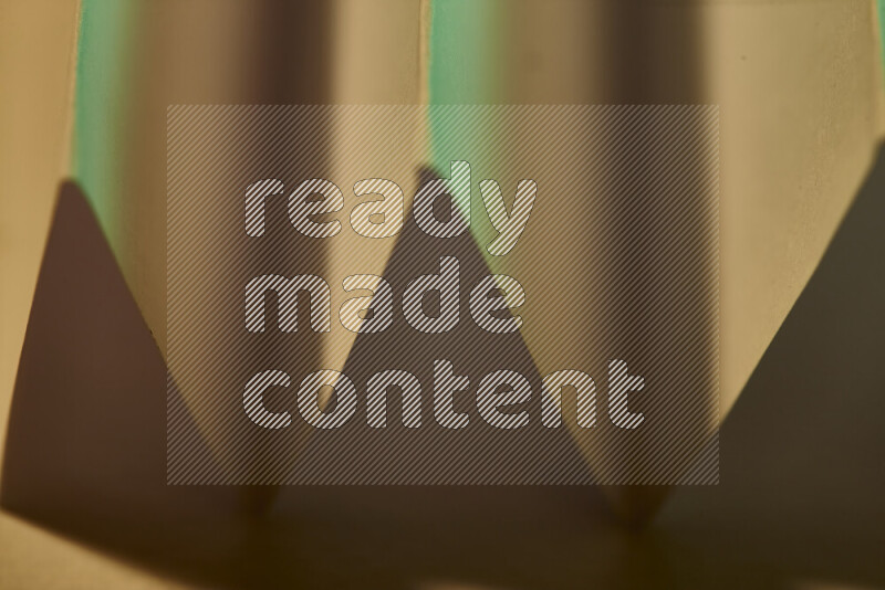 A close-up abstract image showing sharp geometric paper folds in green gradients and warm tones