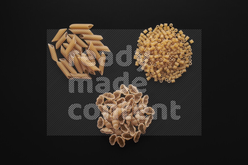 Different pasta types in bunches on black background
