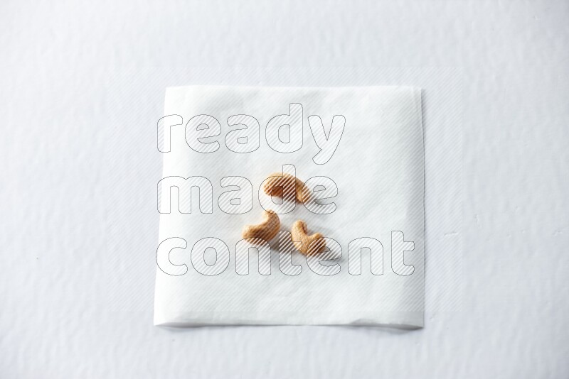 3 cashews on a piece of paper on a white background in different angles
