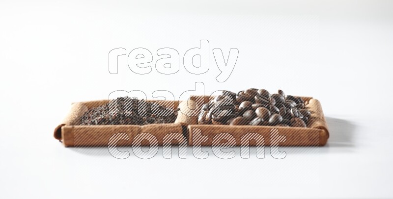 مربعان من أعواد القرفة ممتلئان بحبوب القهوة والشاي الأسود علي خلفية بيضاء