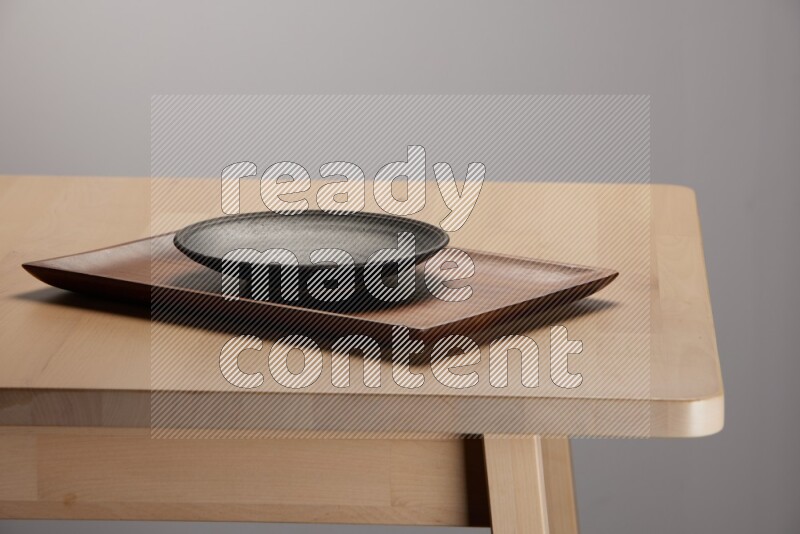 black plate on a rectangular wooden tray on the edge of wooden table