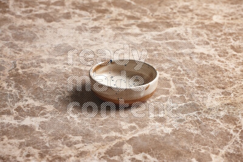 A multicolored pottery plate on beige marble background