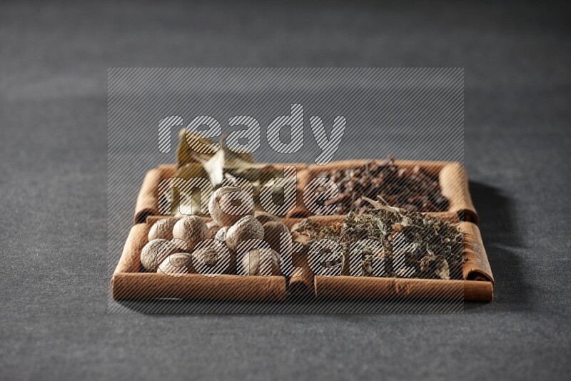 4 squares of cinnamon sticks full of bay laurel leaves, dried basil, cloves and nutmegs on black flooring