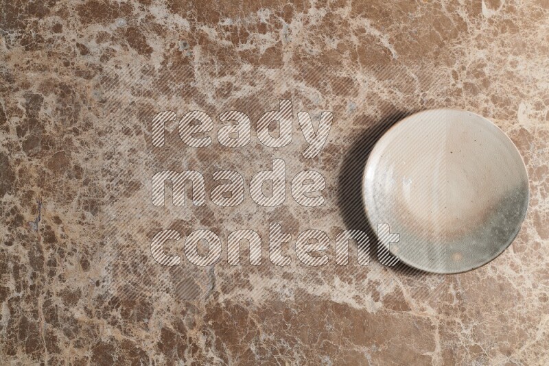 A multicolored pottery plate on beige marble background