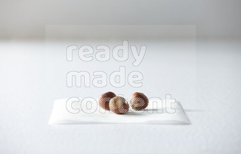 3 hazelnuts on a piece of paper on a white background in different angles