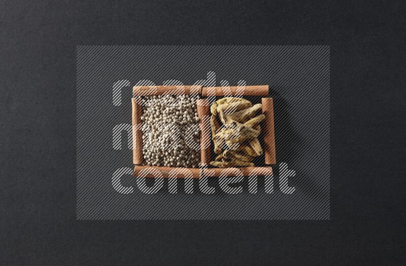 2 squares of cinnamon sticks full of white pepper and turmeric fingers on black flooring