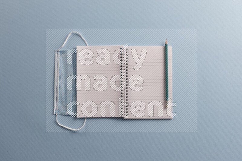 A blank open notebook with different school supplies on blue background