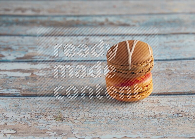 45º Shot of of two assorted Brown Irish Cream, and Orange Exotic macarons on light blue background