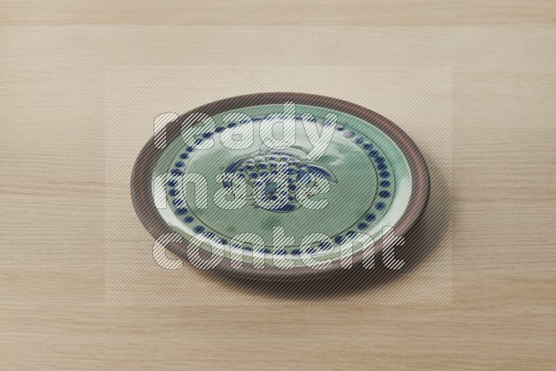 A decorative pottery plate on light wooden background
