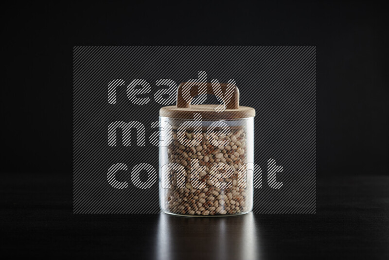 Black-eyed peas in a glass jar on black background