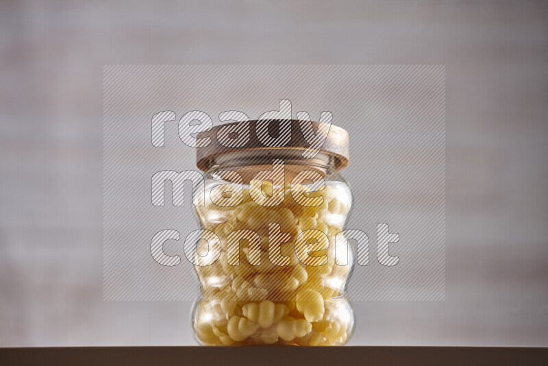 Raw pasta in glass jars on beige background