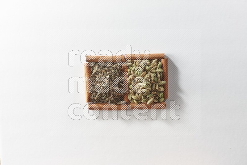 2 squares of cinnamon sticks full of cardamom and dried basil on white flooring