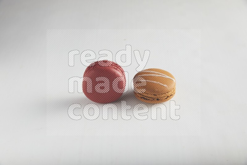 45º Shot of of two assorted Brown Irish Cream, and Red Velvet macarons on white background