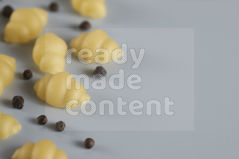 Raw pasta with different ingredients such as cherry tomatoes, garlic, onions, red chilis, black pepper, white pepper, bay laurel leaves, rosemary, cardamom and mushrooms on light blue background