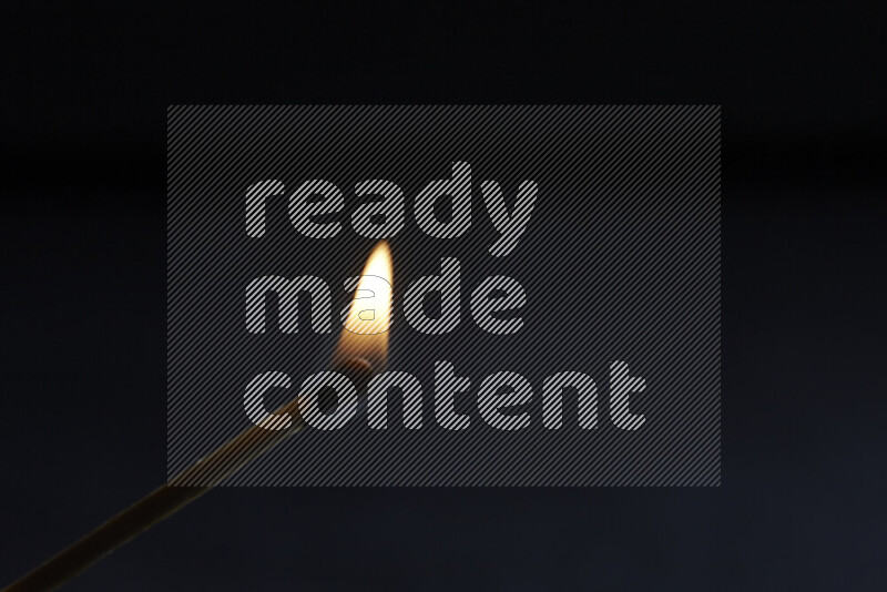 A burning matchstick isolated on dark backdrop