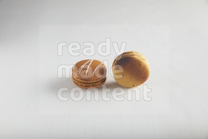 45º Shot of of two assorted Brown Irish Cream, and Yellow Crème Brulée macarons on white background