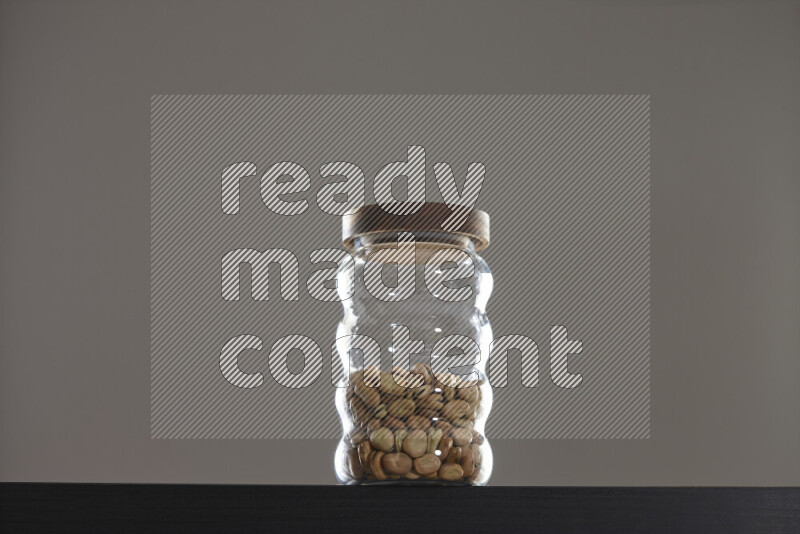 Fava beans in a glass jar on black background