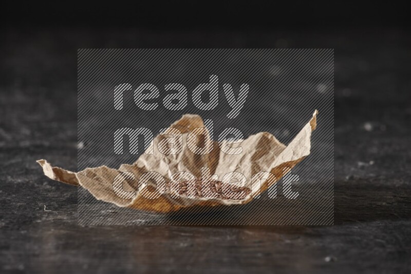 حبوب بذر الكتان في قطعة من الورق علي خلفية سوداء