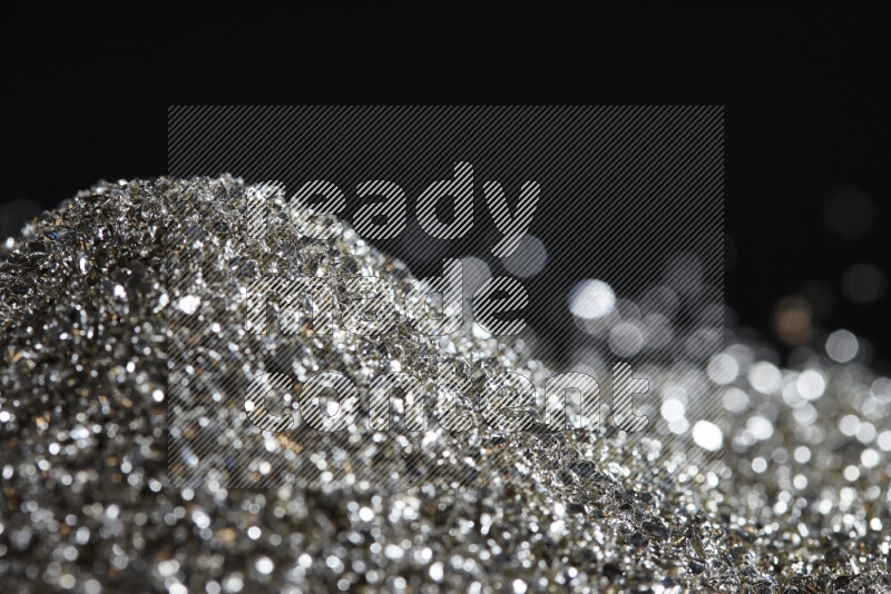 Silver shimmering fragments of glass scattered on a black background