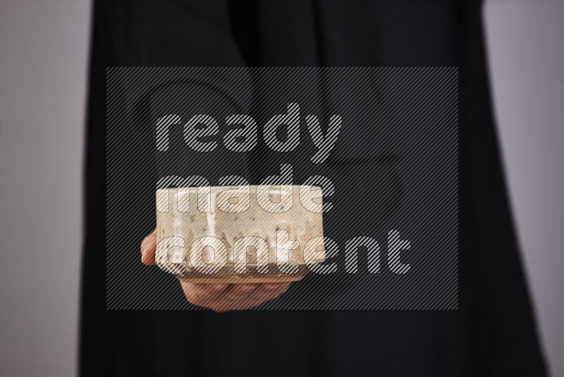 A woman in black abaya holding different pottery essentials in different positions