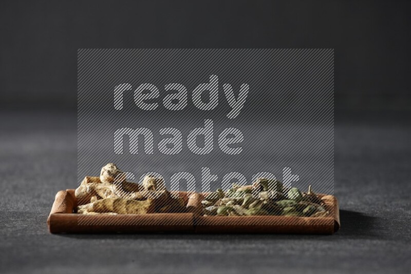 2 squares of cinnamon sticks full of cardamom and turmeric fingers on black flooring