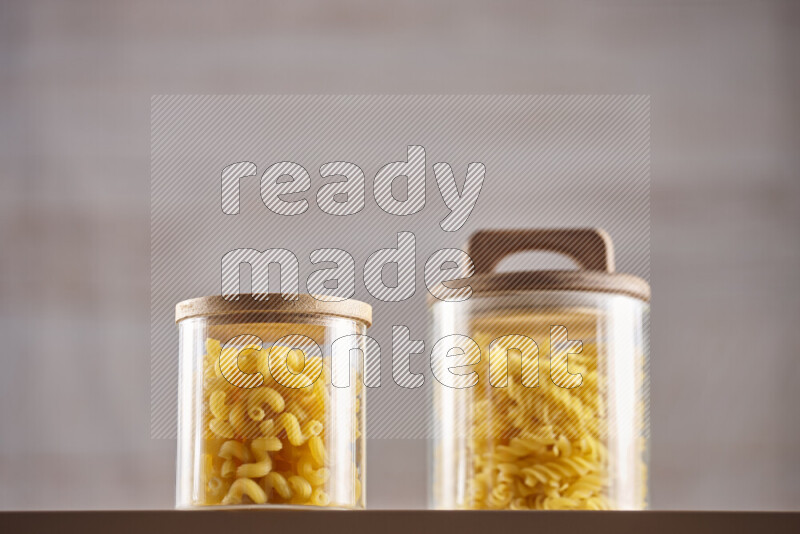 Raw pasta in glass jars on beige background