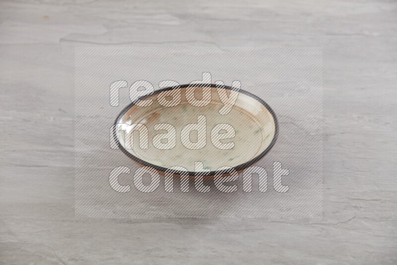 multi color ceramic round plate on grey textured countertop