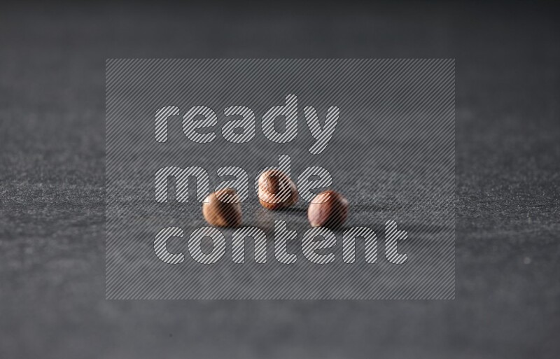 3 peeled hazelnuts on a black background in different angles