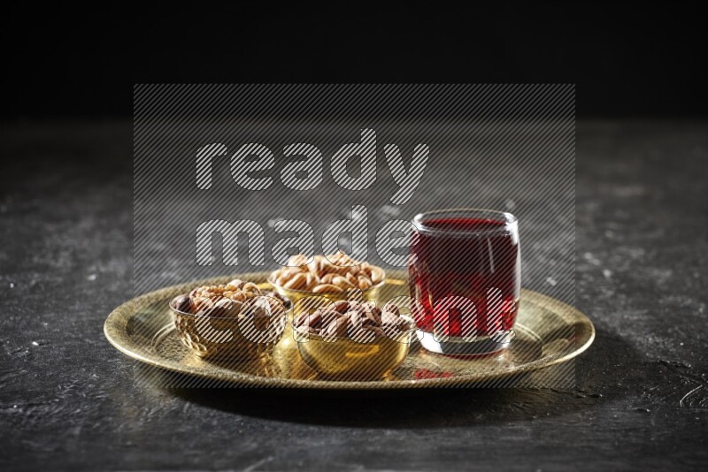 Nuts in metal bowls with Hibiscus on a tray in dark setup