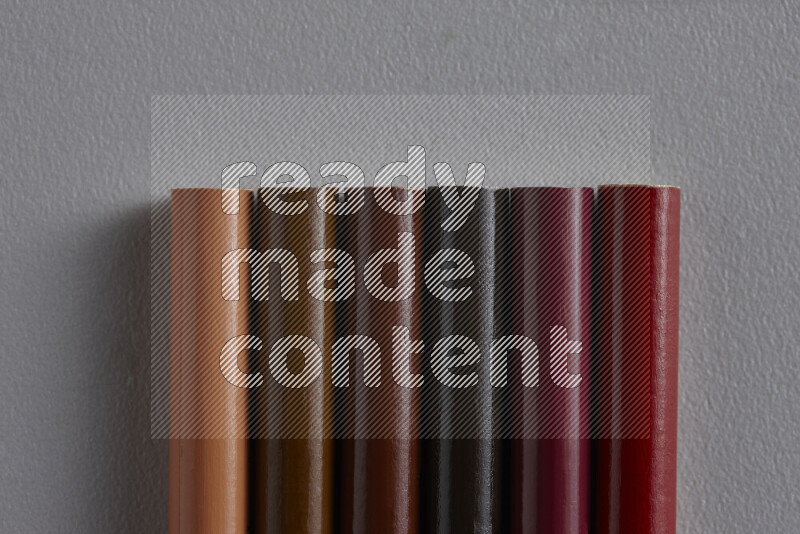 A collection of colored pencils arranged showcasing a gradient of brown hues on grey background
