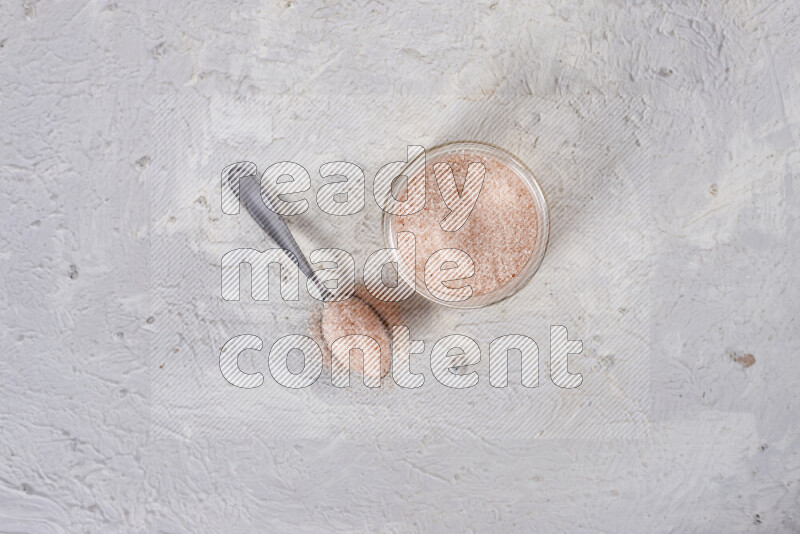 A glass jar full of fine himalayan salt on white background