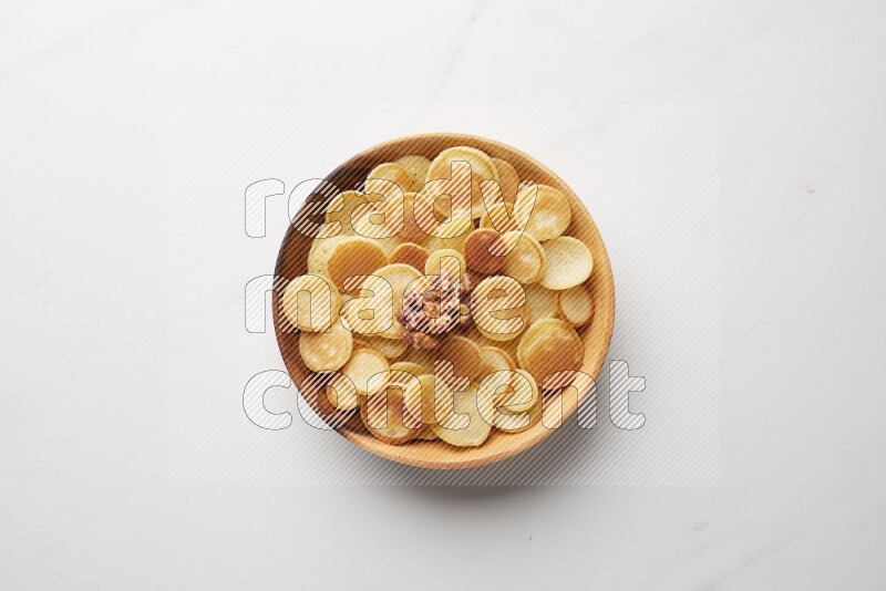 Top-view shot of walnut cereal pancakes in a round bowl on white background
