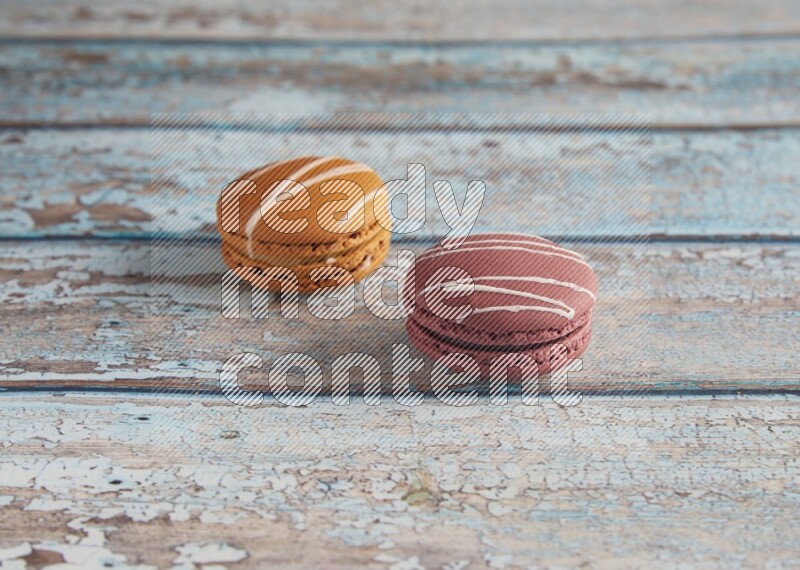 45º Shot of of two assorted Brown Irish Cream, and Red Poppy Flower macarons  on light blue background