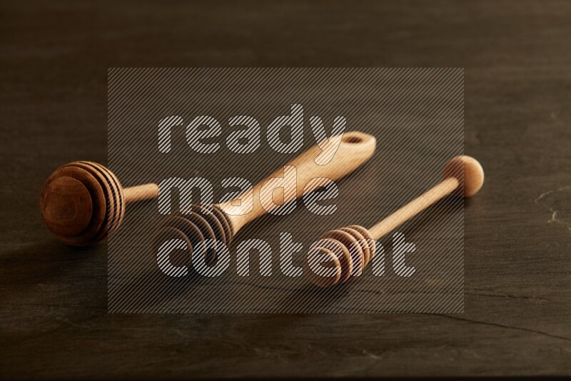 Wooden honey dipper on black slate background