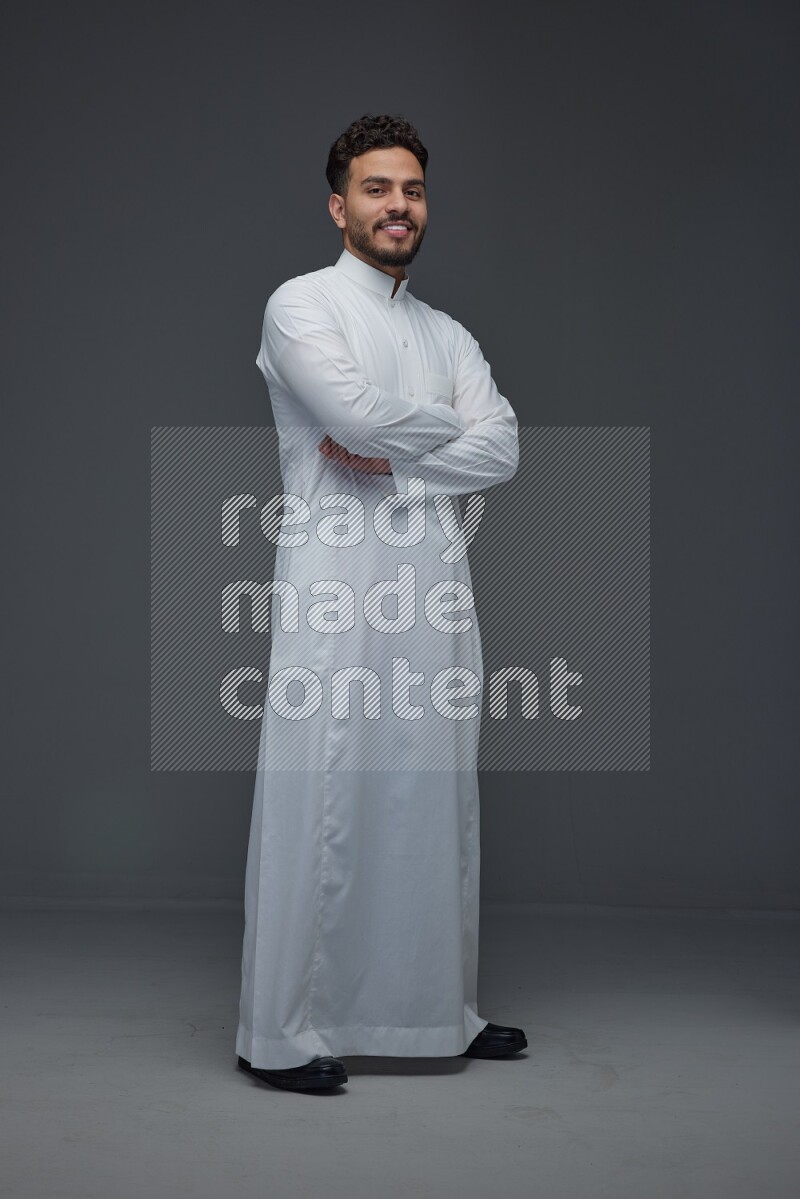 A Saudi man wearing Thobe standing and making different poses eye level on a gray background
